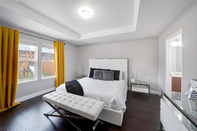 bedroom featuring a raised ceiling, dark wood-type flooring, and ensuite bath