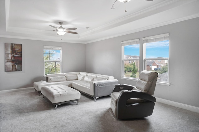 carpeted living room with a tray ceiling, ceiling fan, and crown molding