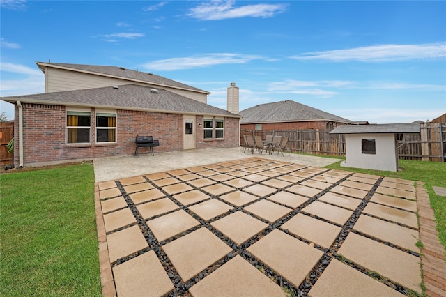 rear view of property with a patio area, a yard, and a storage shed