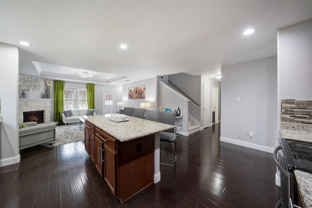 kitchen featuring a fireplace, dark hardwood / wood-style floors, a kitchen island, and black range