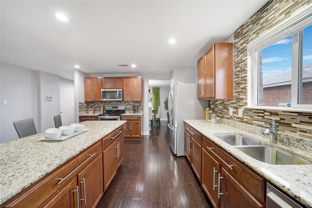 kitchen with decorative backsplash, light stone counters, dark wood-type flooring, and appliances with stainless steel finishes