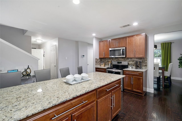 kitchen featuring tasteful backsplash, light stone counters, dark hardwood / wood-style floors, and appliances with stainless steel finishes