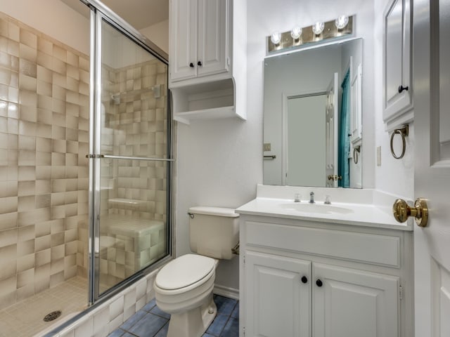 bathroom featuring tile patterned floors, vanity, toilet, and a shower with shower door