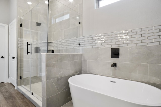 bathroom featuring tile walls, wood-type flooring, and independent shower and bath