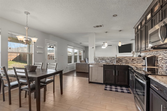 kitchen featuring dark brown cabinetry, a wealth of natural light, decorative light fixtures, and light stone counters