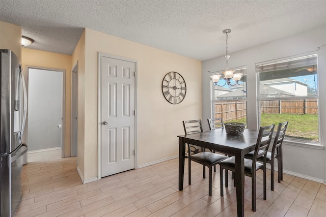 dining room with light hardwood / wood-style flooring, a textured ceiling, and a chandelier