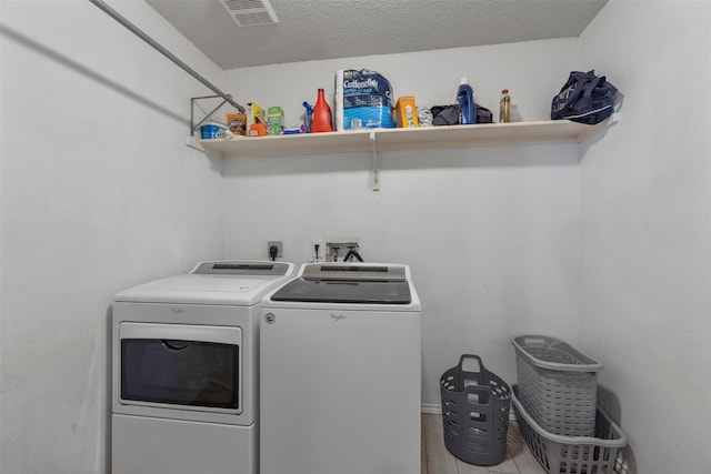 laundry room featuring light hardwood / wood-style floors, a textured ceiling, and washer and clothes dryer