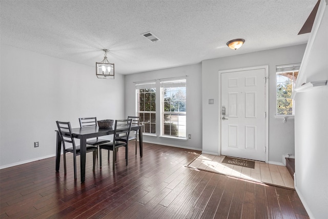 dining room with a chandelier, a textured ceiling, and dark hardwood / wood-style flooring