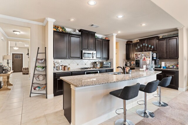 521 Butterfly Blvd, Prosper, TX 75078 - kitchen featuring appliances with stainless steel finishes, a sink, crown molding, a breakfast bar area, and tasteful backsplash