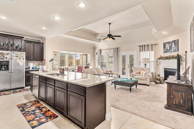 kitchen with stainless steel appliances, dark brown cabinetry, light carpet, sink, and an island with sink