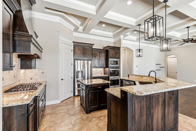 kitchen with appliances with stainless steel finishes, decorative light fixtures, decorative backsplash, sink, and an island with sink