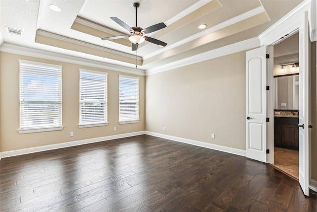 spare room featuring dark wood-type flooring, a tray ceiling, and crown molding