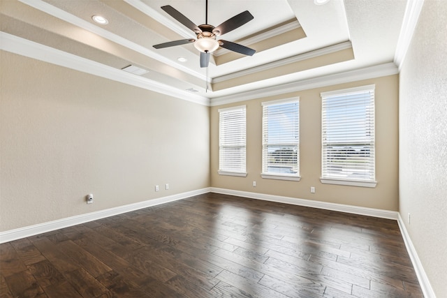 unfurnished room featuring dark hardwood / wood-style floors, a tray ceiling, a healthy amount of sunlight, and crown molding