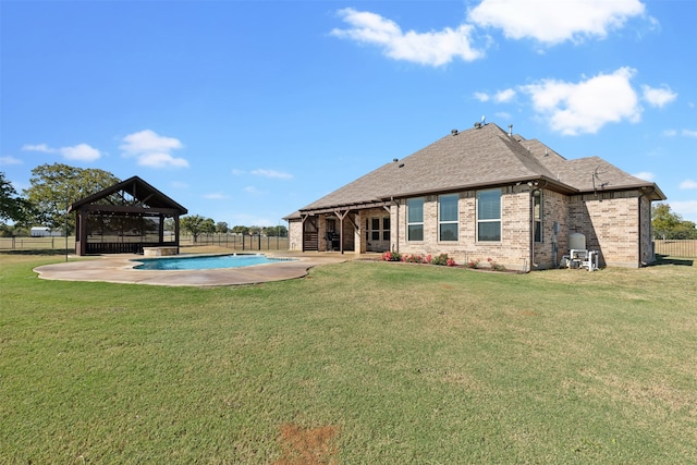 rear view of house featuring a fenced in pool, a patio, and a yard