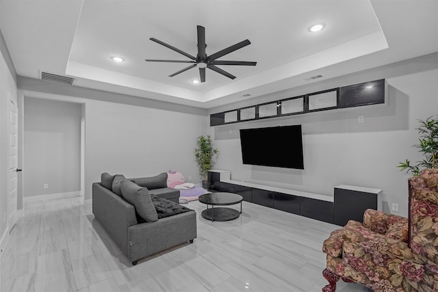 living room with ceiling fan and a tray ceiling