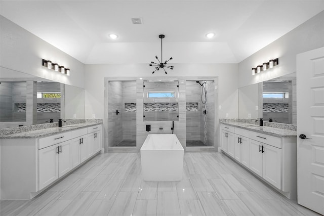 bathroom featuring independent shower and bath, vanity, an inviting chandelier, and a tray ceiling