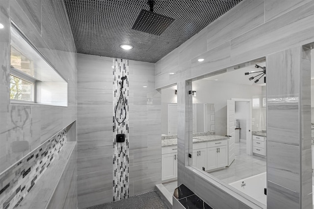 bathroom with tile walls, tile patterned flooring, vanity, and tiled shower