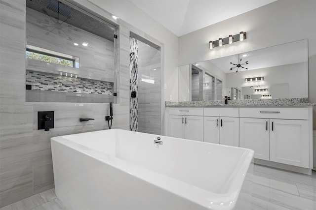 bathroom with tile walls, vanity, shower with separate bathtub, a notable chandelier, and lofted ceiling