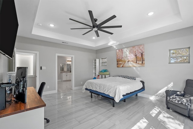 bedroom featuring a raised ceiling, ceiling fan, and ensuite bathroom