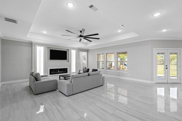 living room featuring a tray ceiling, french doors, ceiling fan, and crown molding