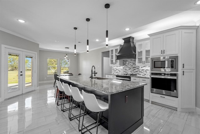 1055 Encino Ct, Wills Point, TX 75169 - kitchen featuring stainless steel appliances, a sink, premium range hood, crown molding, and an island with sink