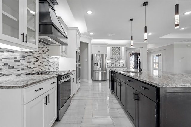 kitchen with white cabinetry, appliances with stainless steel finishes, custom range hood, and hanging light fixtures