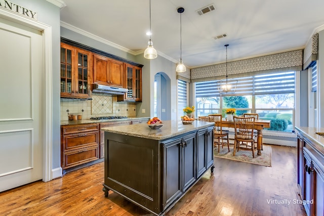 kitchen featuring pendant lighting, a center island, light stone counters, and gas stovetop