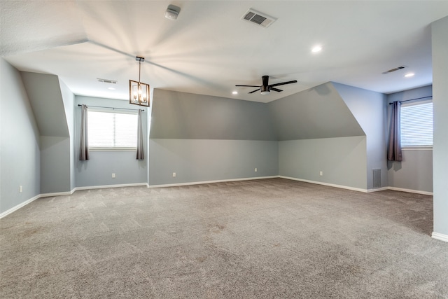 additional living space with vaulted ceiling, light colored carpet, and ceiling fan with notable chandelier