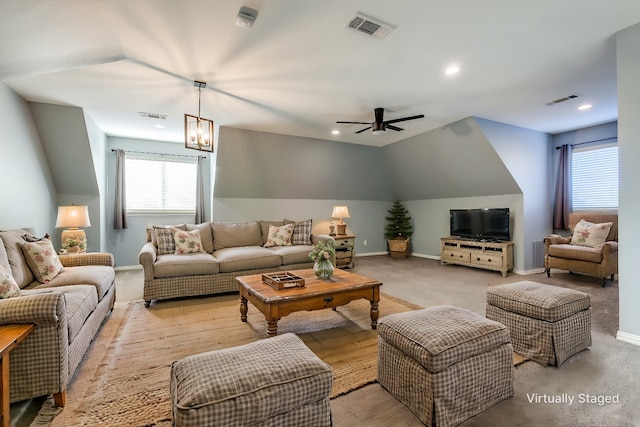 carpeted living room featuring ceiling fan with notable chandelier and vaulted ceiling