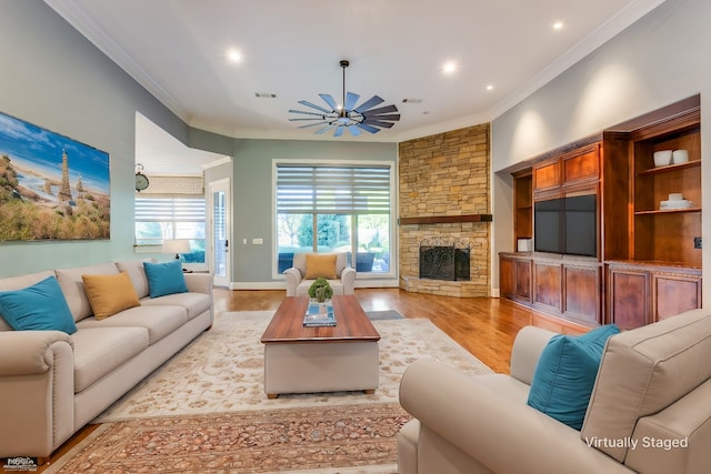 living room featuring ornamental molding, plenty of natural light, a fireplace, and light wood-type flooring