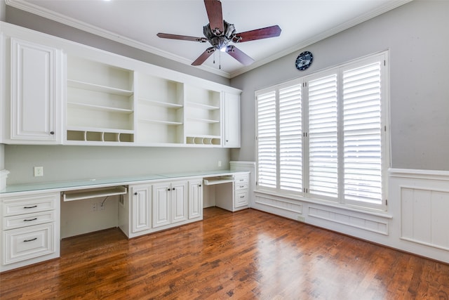 unfurnished office with crown molding, built in desk, and dark wood-type flooring