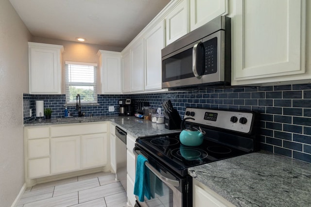 kitchen featuring white cabinets, sink, decorative backsplash, light stone countertops, and appliances with stainless steel finishes