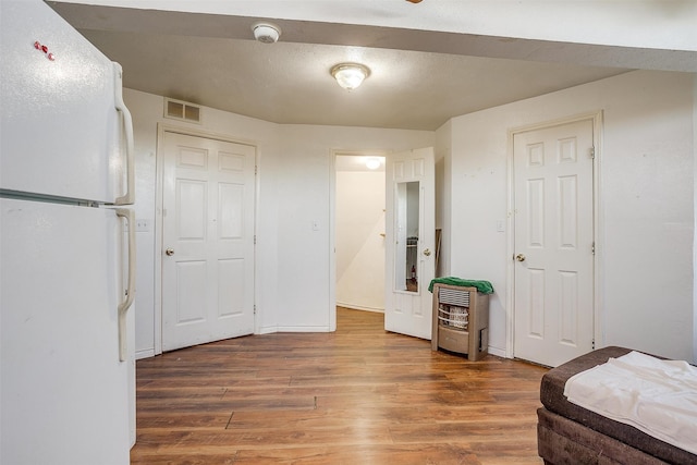 bedroom featuring wood-type flooring and white fridge