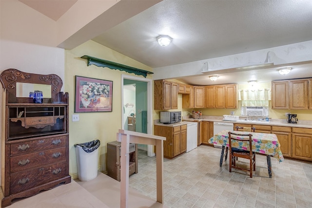 kitchen featuring lofted ceiling, a textured ceiling, white dishwasher, and sink