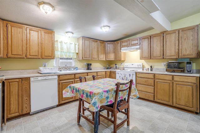 kitchen featuring sink, white appliances, a textured ceiling, and lofted ceiling