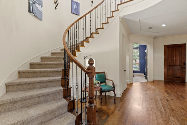 staircase with hardwood / wood-style floors and ornamental molding