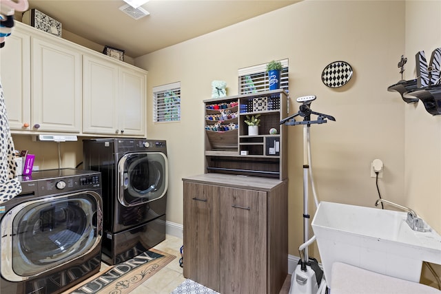 laundry room with washing machine and dryer, cabinets, and light tile patterned floors