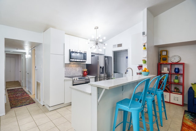 kitchen with white cabinetry, stainless steel appliances, light tile patterned floors, and vaulted ceiling