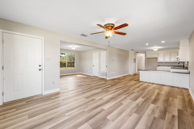 unfurnished living room with ceiling fan, sink, and light hardwood / wood-style floors