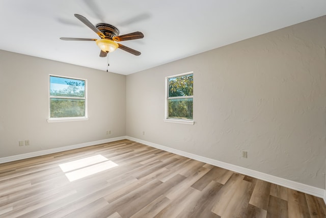empty room with a wealth of natural light, ceiling fan, and light hardwood / wood-style flooring