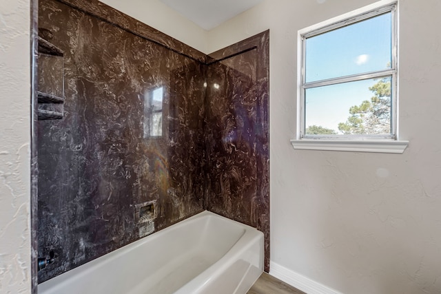 bathroom with a wealth of natural light and tiled shower / bath