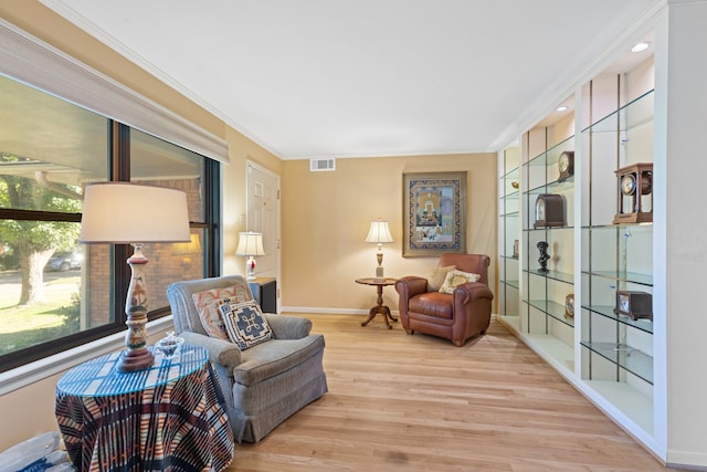 sitting room with light hardwood / wood-style flooring and crown molding