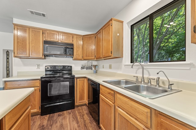 kitchen with black appliances, dark hardwood / wood-style flooring, and sink