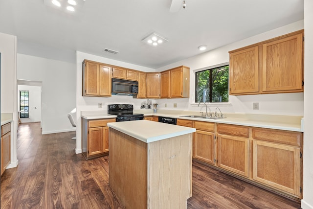 kitchen featuring black appliances, dark hardwood / wood-style flooring, sink, and a center island