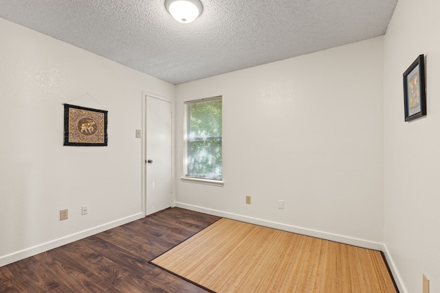 unfurnished room with dark wood-type flooring and a textured ceiling