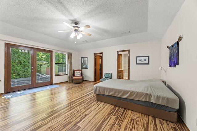 bedroom featuring ensuite bath, ceiling fan, a textured ceiling, access to exterior, and light wood-type flooring