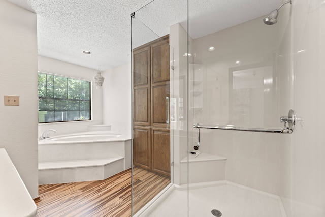 bathroom featuring shower with separate bathtub, wood-type flooring, and a textured ceiling