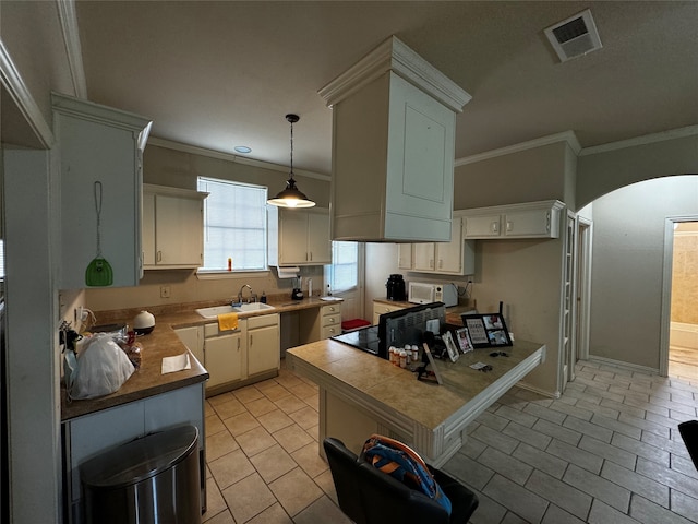 kitchen featuring hanging light fixtures, crown molding, stove, and white cabinets