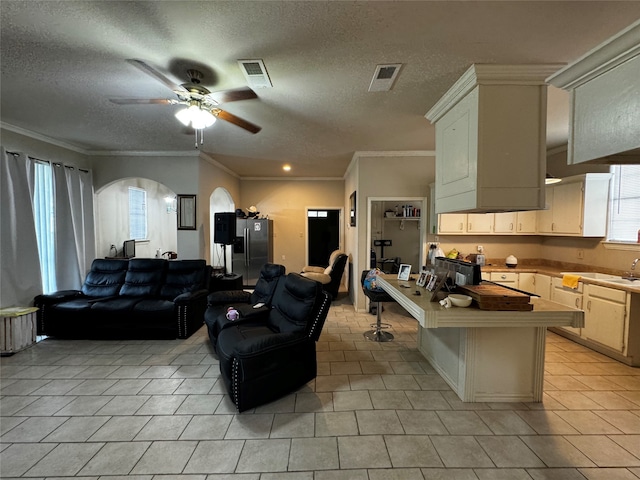 kitchen with ceiling fan, a textured ceiling, light tile patterned floors, and ornamental molding