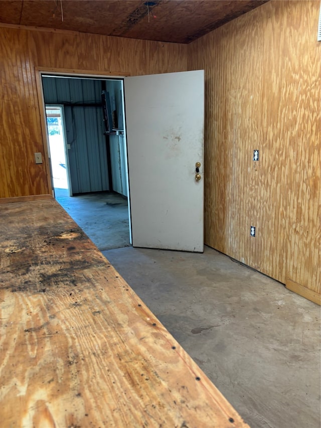 unfurnished room featuring concrete flooring and wooden walls